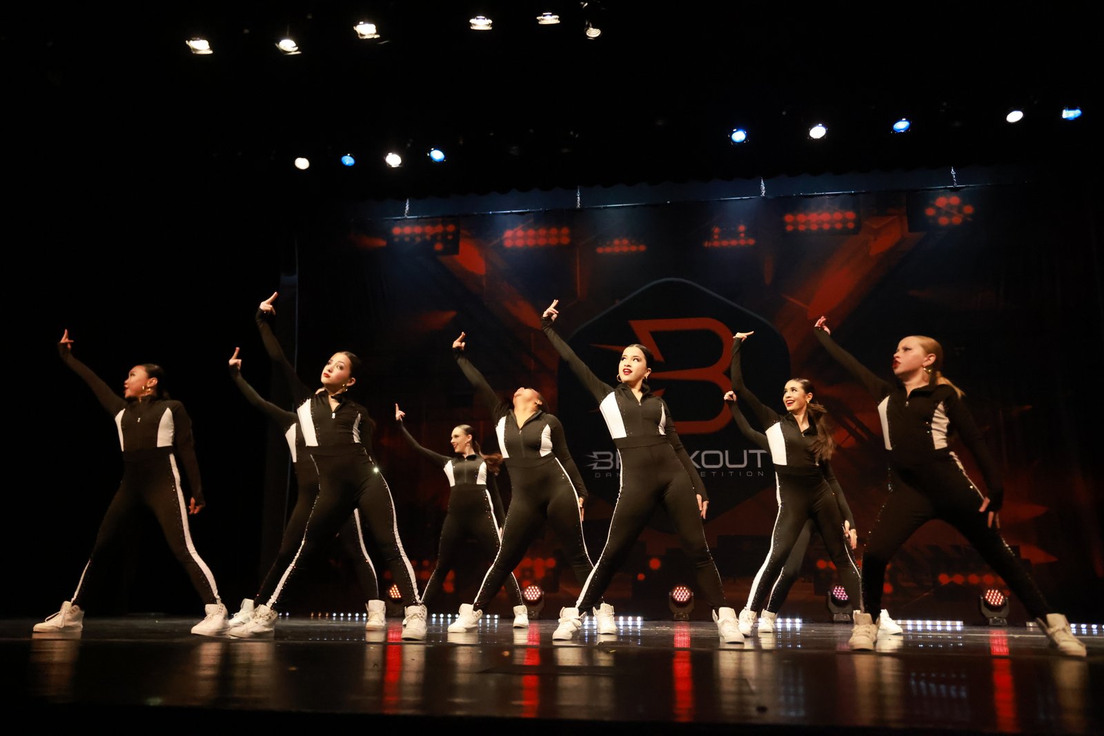 Studio L competition dancers performing a synchronized routine on a lit stage
