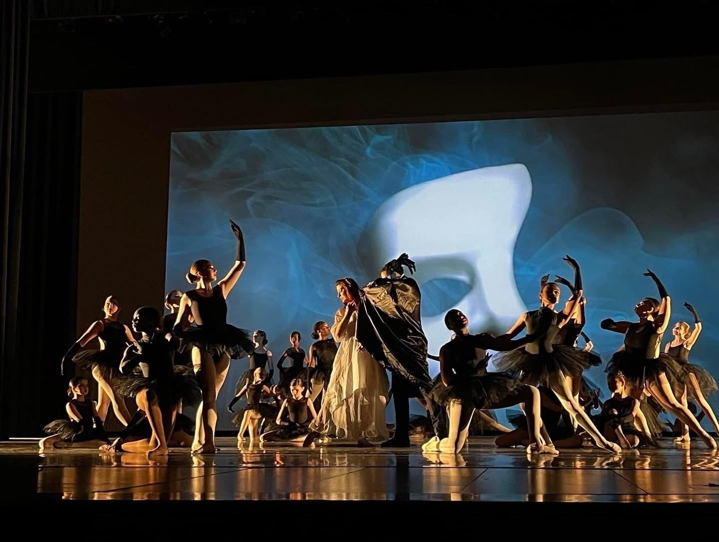 Studio L dancers performing together on stage under warm lighting at the annual recital