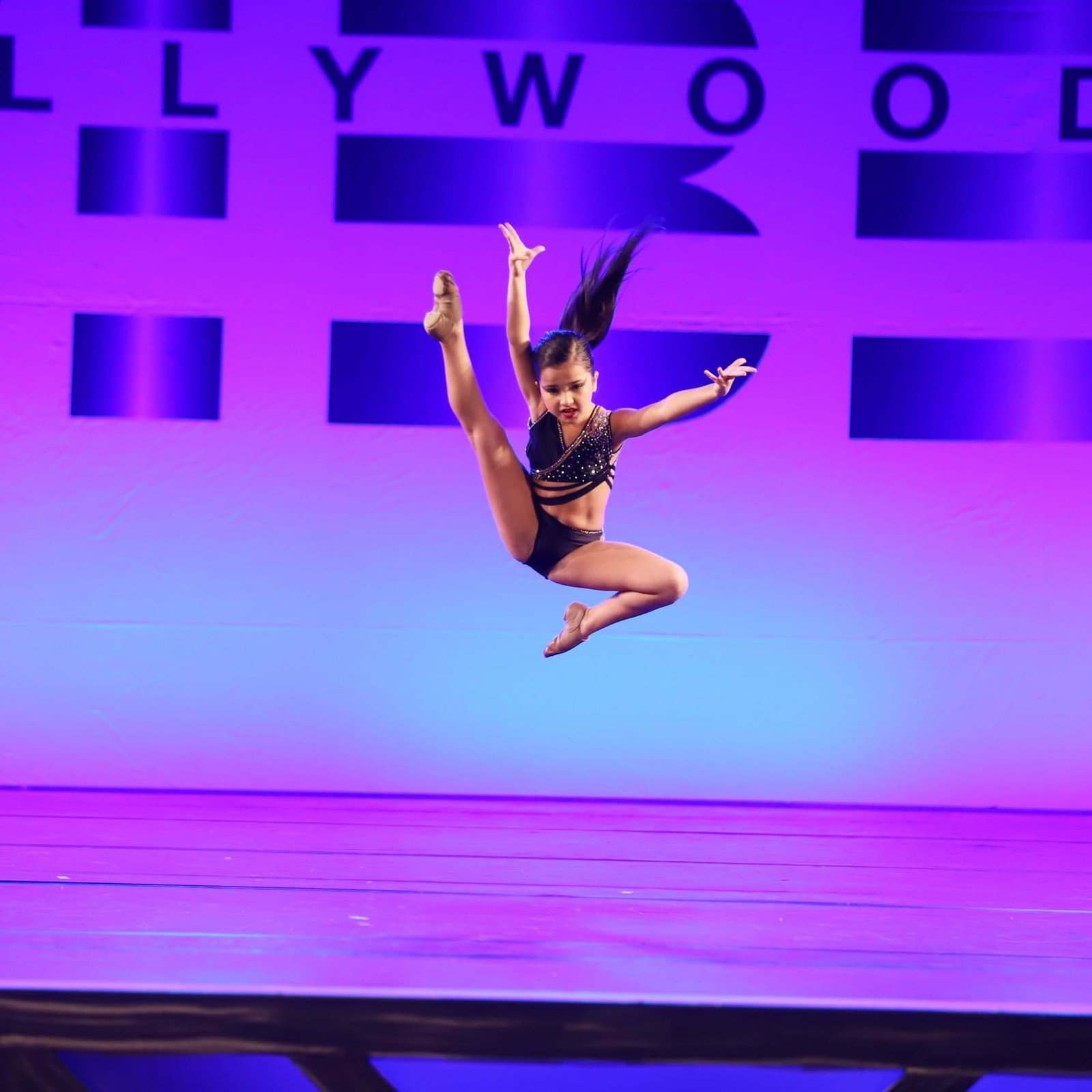 Solo dancer at the peak of a leap on a competition stage